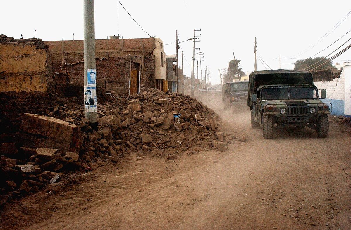 Calle de Pisco con casas de adobe derrumbadas y vehículos militares, tras el terremoto de 2007